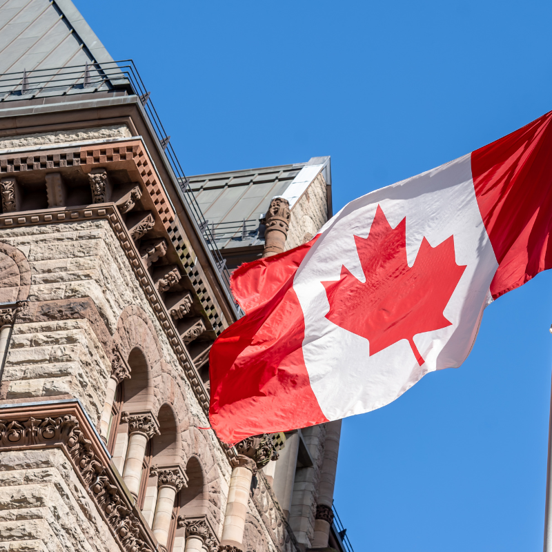 Image of a building partially being covered by Canadian Flag.
