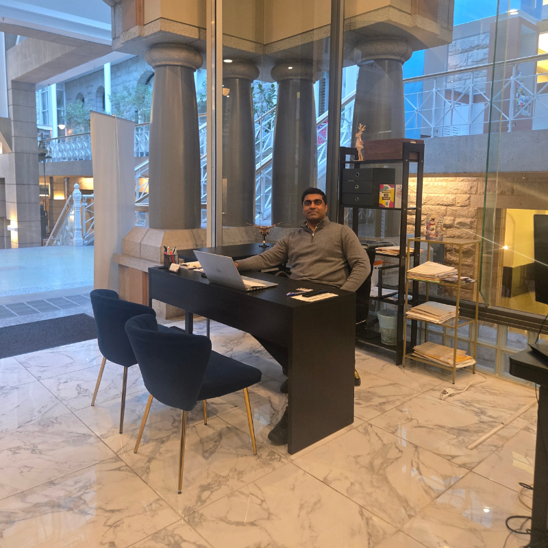 Work Permit RCIC Mathai sitting on a chair in our Vancouver Office in Sinclair Centre, Specialised in CUSMA work permit cases and well versed in explaining CUSMA Work Permit Requirements to US Citizens